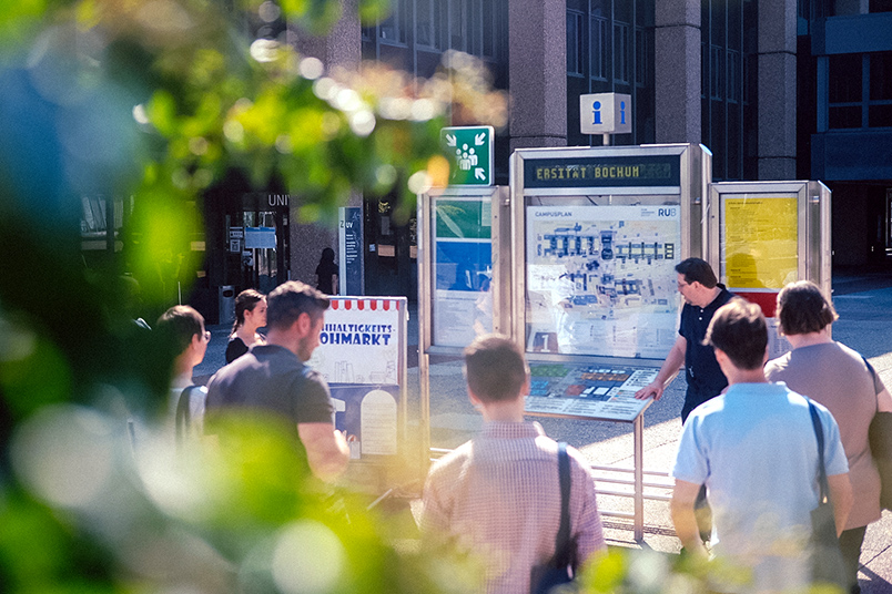 Eine Gruppe steht vor einer Informationstafel auf dem Campus der Ruhr-Universität Bochum.