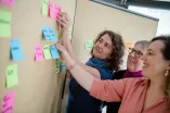 Kolleginnen des OEPE-TEams strukturieren Beiträge an der Pinnwand.