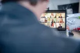 Person vor Rechner mit Videokonferenz