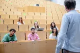 Studierende sitzen in einem Hörsaal und schauen den Dozenten an.