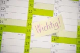 Hand klebt Post-it mit Aufschrift Wichtig auf einen Kalender.