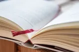 Foto: Aufgeschlagenes Buch, unscharf, mit roten Lesezeichen