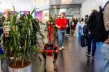 Photo: Career fair at the Convention Center Ruhr University Bochum. The forum is filled with visitors and booths. In the center of the photo is a red, four-legged robot being controlled by a man in a red T-shirt.
