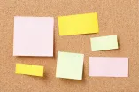 Bunte leere Postits auf Korkwanda