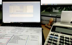 Mappe, PC, Rechenmaschine, Stempel und ein Dokument auf dem Schreibtisch ausgebreitet. 