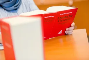 Eine Person hält ein Buch mit dem Titel "Deutsche Gesetze" in der Hand