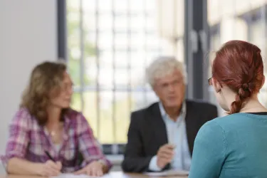 Studierende und zwei Prüfer in einer Prüfungssituation