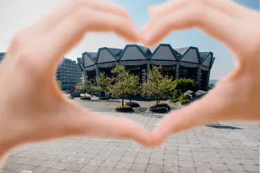 Ein Bild auf das Audimax durch zum Herz geformte Hände