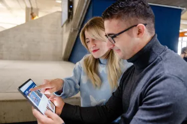 Eine Frau zeigt einem Mann etwas auf einem Tablet.