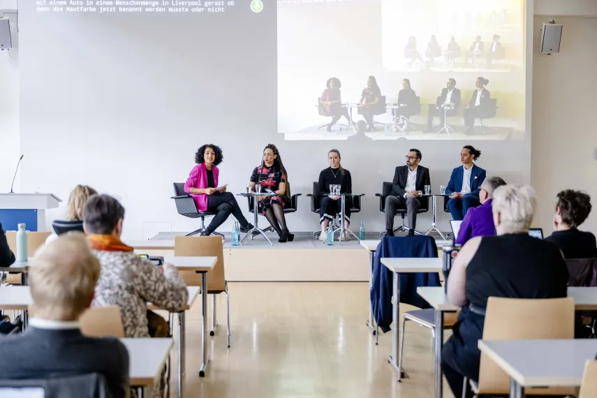 Foto: Podiumsdiskussion mit 5 Speaker*innen und Publikum