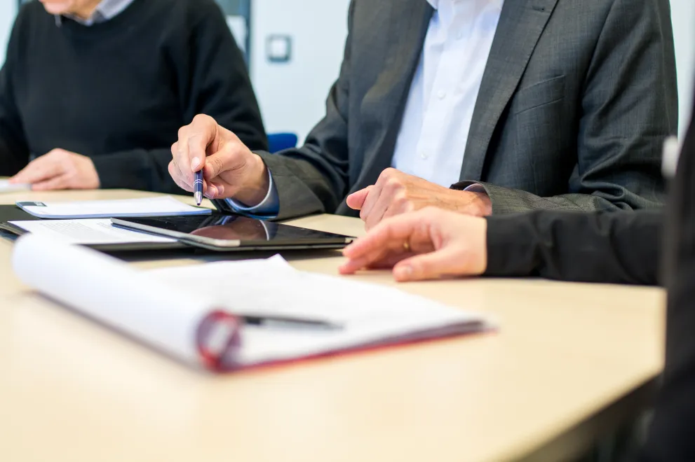 Tisch beim Meeting mit Unterlagen und Tablet.