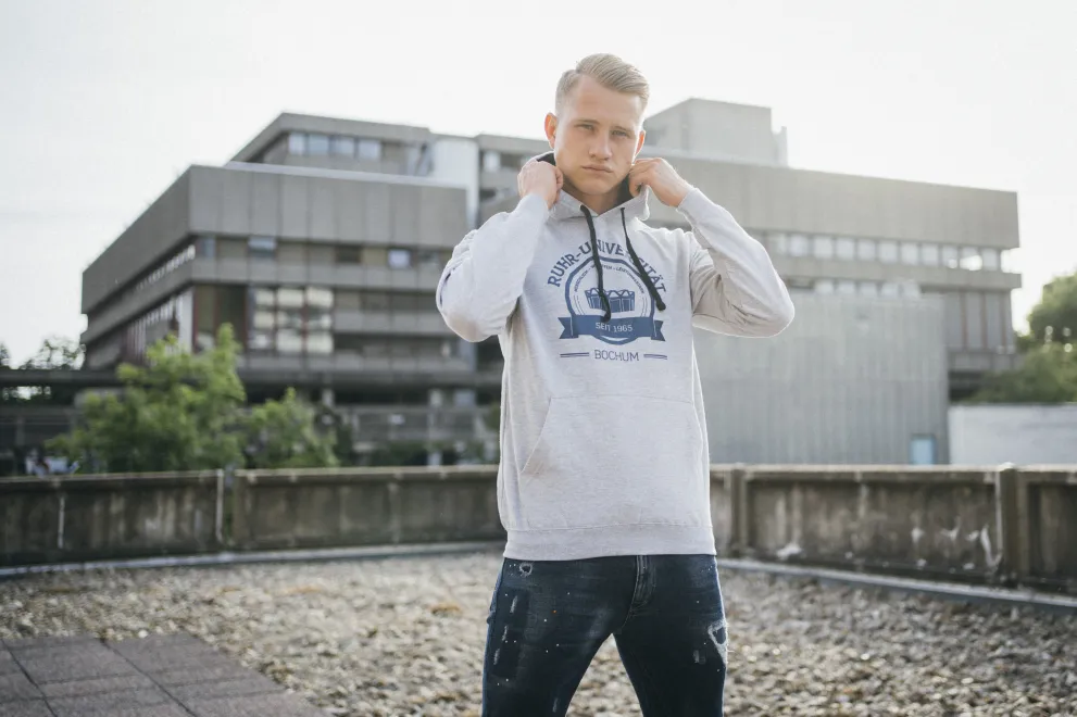 Mann vor Bibliothek mit grauem Hoodie