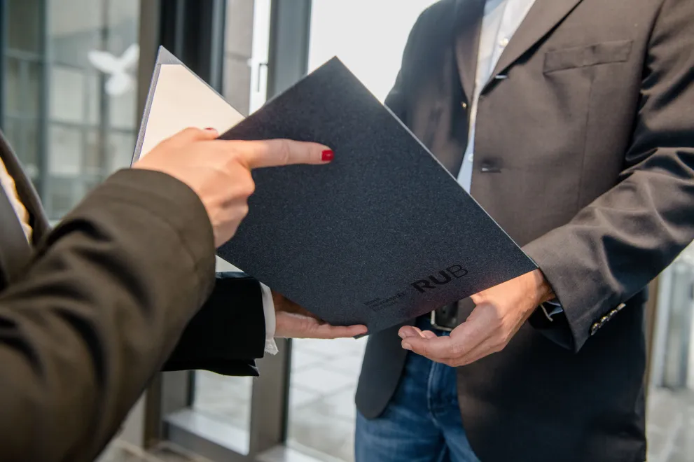 Eine Person überreicht einer anderen eine RUB-Urkunde.