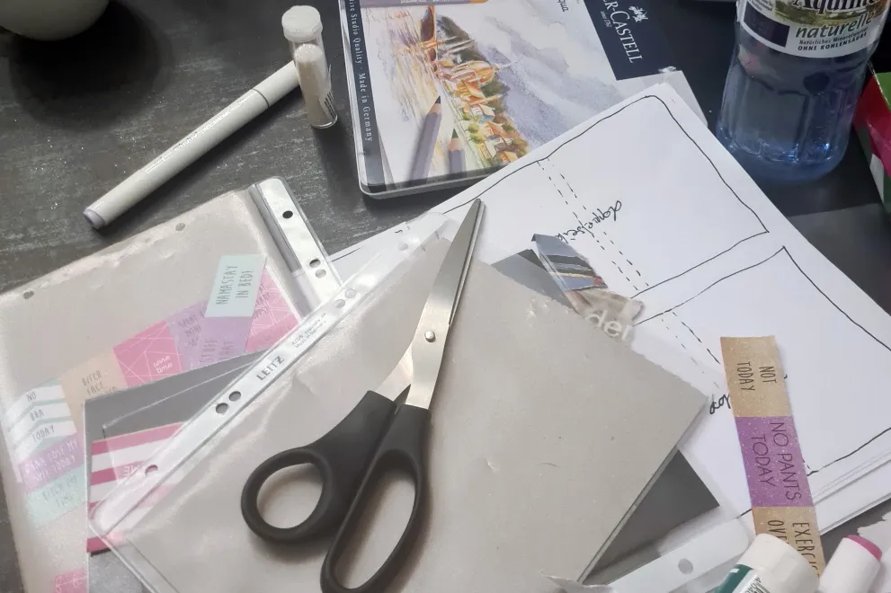Collagematerial wie zum Beispiel Schere, Stift, Papier und vieles mehr liegen auf einem Tisch