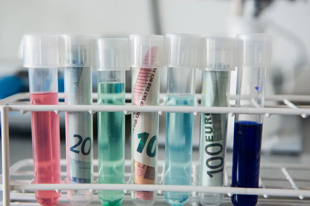 Reagenzgläser und Geldscheine als symbolische Darstellung des Themas finanzielle Abrechnung medizinischer Forschungsprojekte