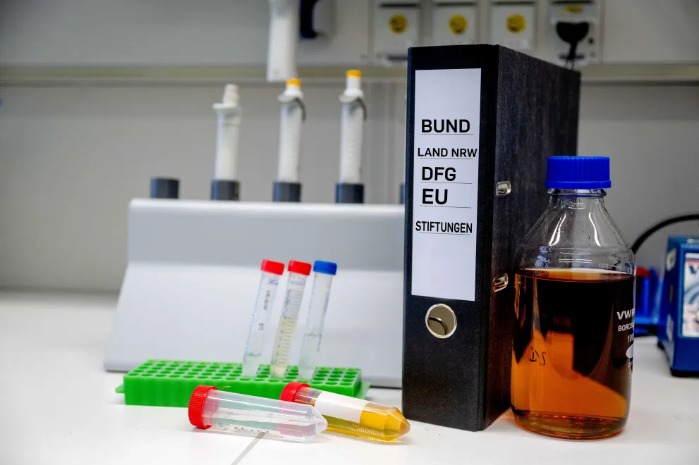 Ordner und Labor als Symbol für Finanzmanagement im Bereich Drittmittel Medizin.