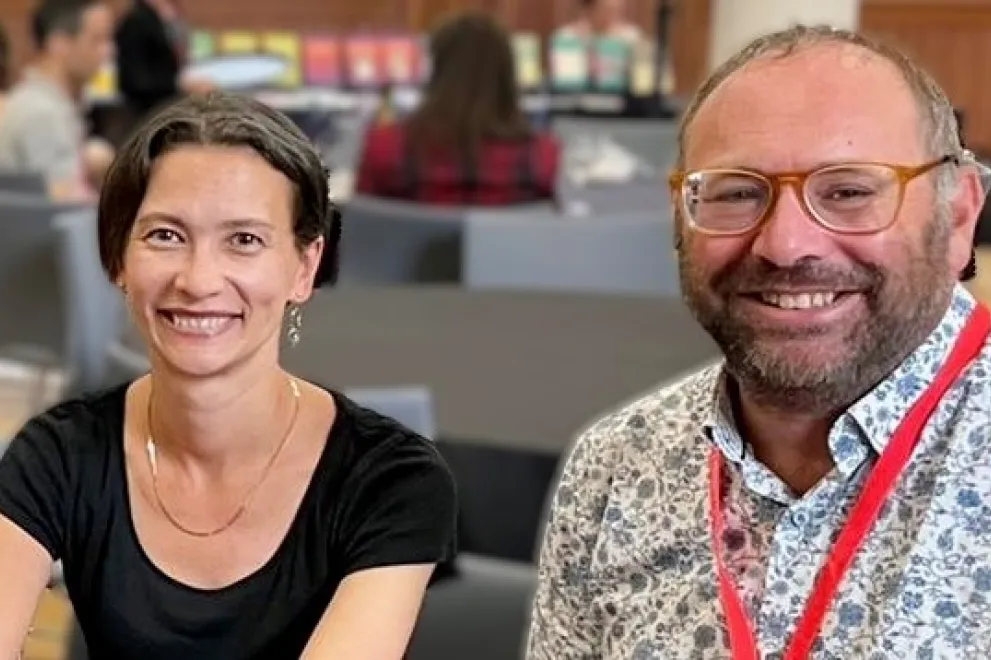 Ben Gidley und Yulia Egorova lächeln in die Kamera, im Hintergrund sind verschwommen Tische und Personen zu erkennen 