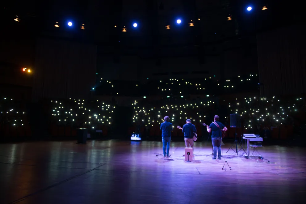 Photo: Band playing in the darkened Audimax, the audience holding up lights.