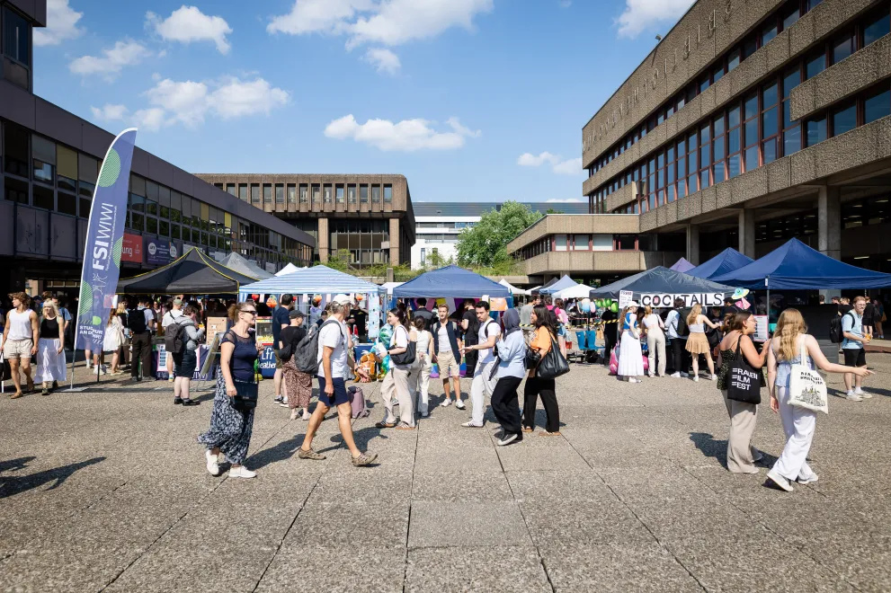 Photo: Stands and visitors in sunny weather at the Nordforum of Ruhr University Bochum