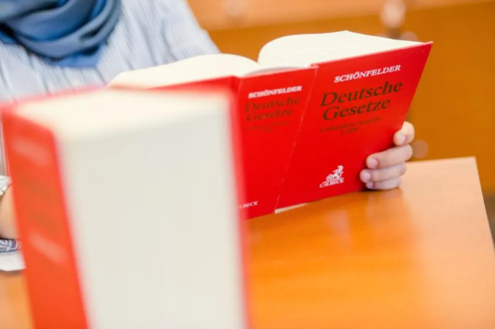 Eine Person hält ein Buch mit dem Titel "Deutsche Gesetze" in der Hand