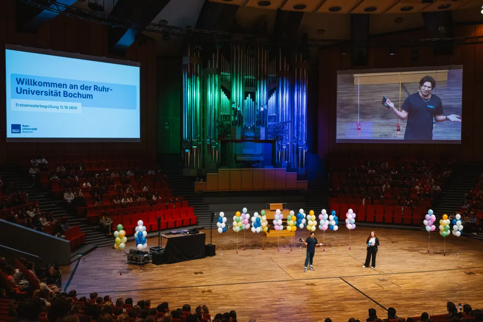 Welcome Ceremony for First-Year Students in the Audimax: View from the seating area toward the stage, side screens, and the illuminated organ