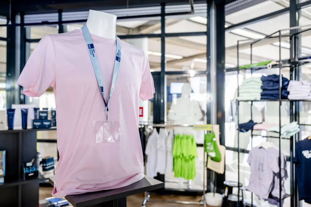 Das Foto zeigt den Unishop auf dem Campus, im Vordergrund einen T-Shirt-Mannequin mit einem RUB-Lanyard um den Hals