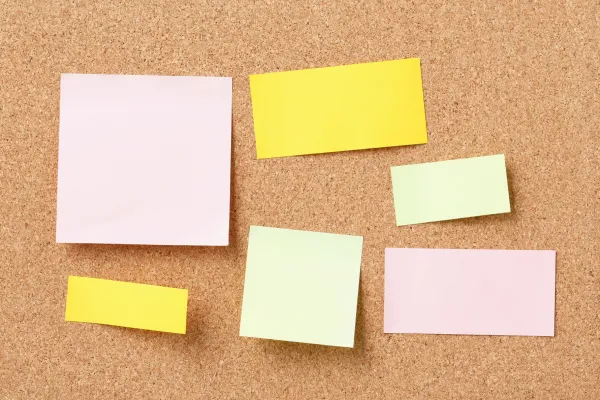 Bunte leere Postits auf Korkwanda