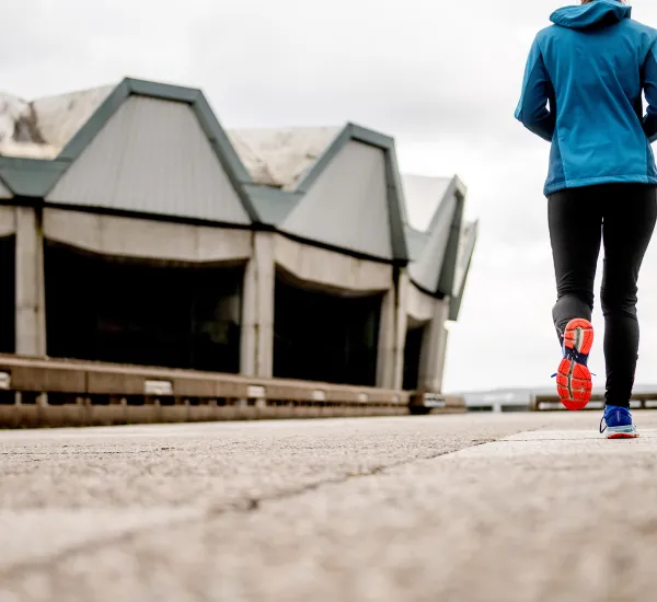 Das Bild zeigt eine Joggerin von hinten, im Hintergrund das Audimax